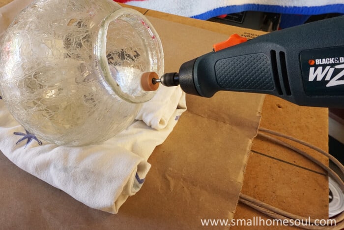 A rotary tool sands the glass globe for the brass lamp.