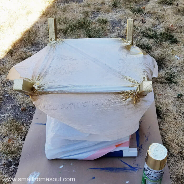 Dip the legs of the folding stool with gold spraypaint.