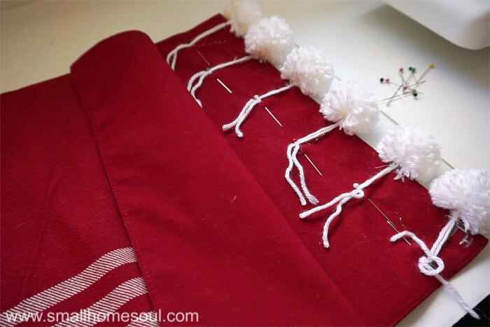 Stitching pom poms to Christmas Pom Pom Pillow.